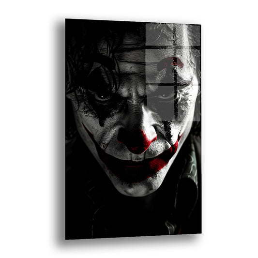 Karanlık Joker cam tablo — koyu bir arka plan önünde, beyaz makyajlı ve kırmızı gülümsemeli sert bir palyaço yüzünü sinematik